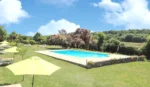 Piscine dans une cour avec un parasol dans l'établissement Hôtel & SPA Château de La Côte - Brantôme, à Biras